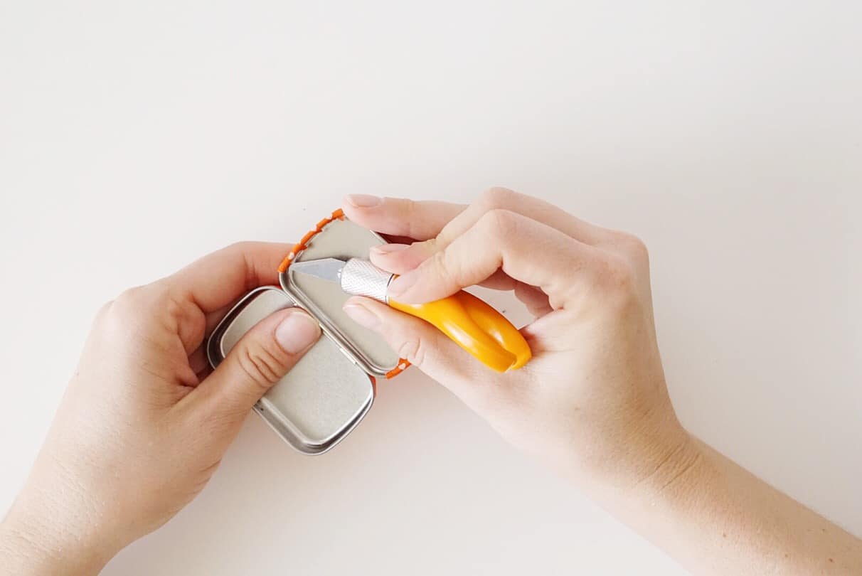 Cutting washi tape around the edge of a Altoids tin
