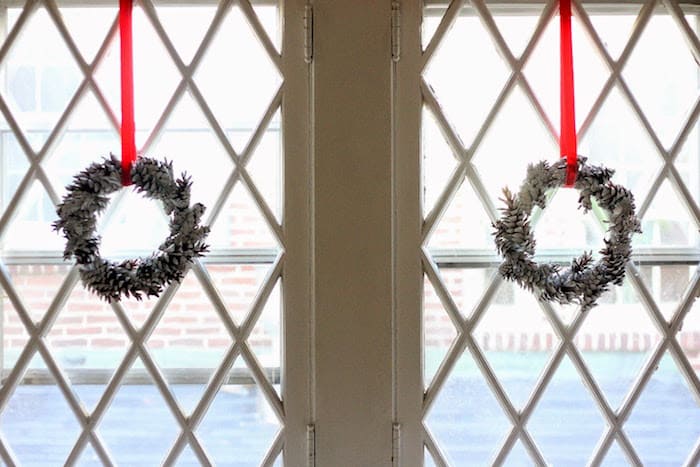 two pine cone wreaths hanging in windows